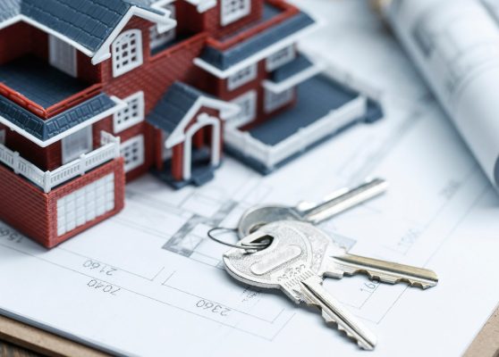 Villa house model, key and drawing on retro desktop (real estate sale concept)